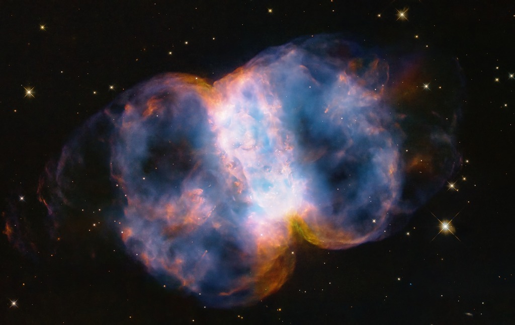 white, orange, and blue nebula resembling a dumbbell