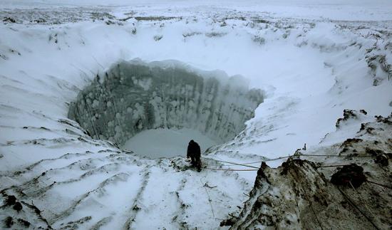 Man looking down a big hole in the ice