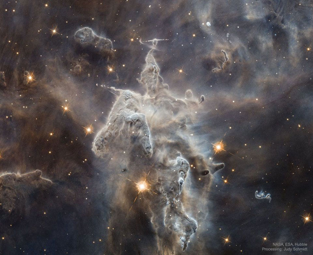 Dramatic white clouds of dust and gas resembling a knight on a horse riding out from a darker nebula full of orange stars.