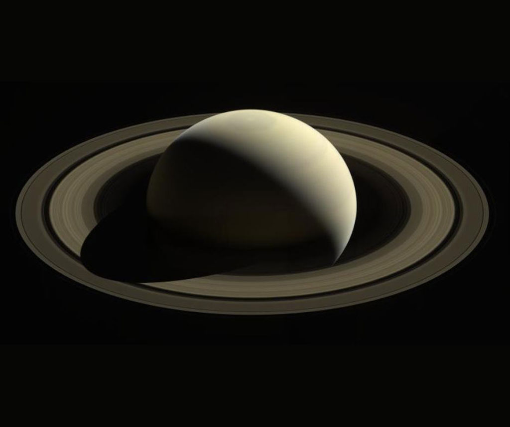 Saturn as seen from above, with the planet casting its shadow halfway across the rings to at seven o'clock. The Cassini Division is distinct in the middle of the two major ring systems.