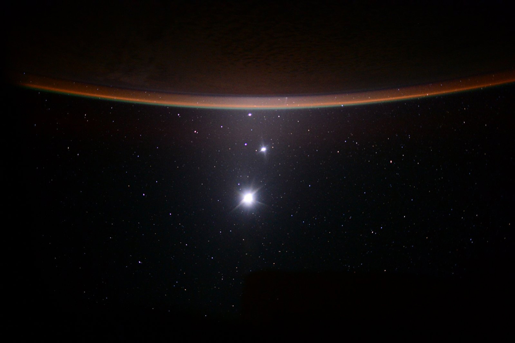 Image of the planets (looking like stars) behind Earth as seen from the ISS
