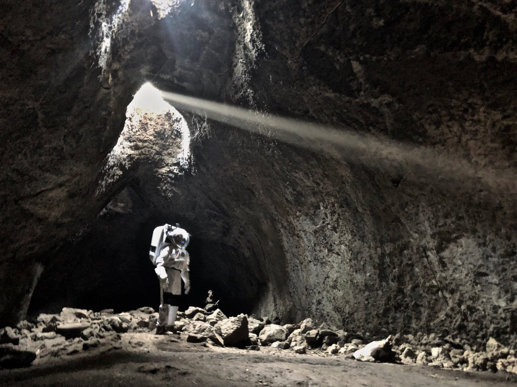 figure wearing a spacesuit in a dark cave