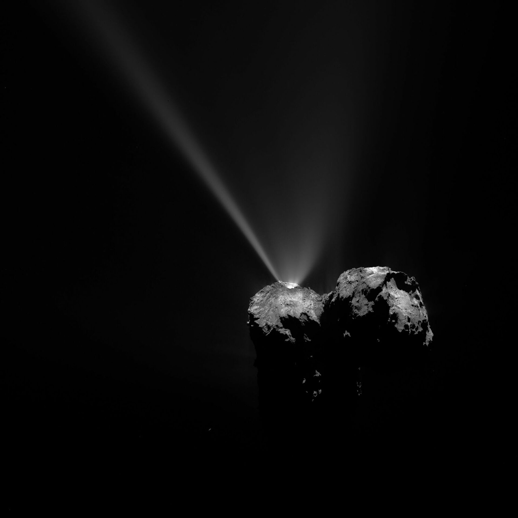 Black and white image of the comet emitting plumes of white smoke