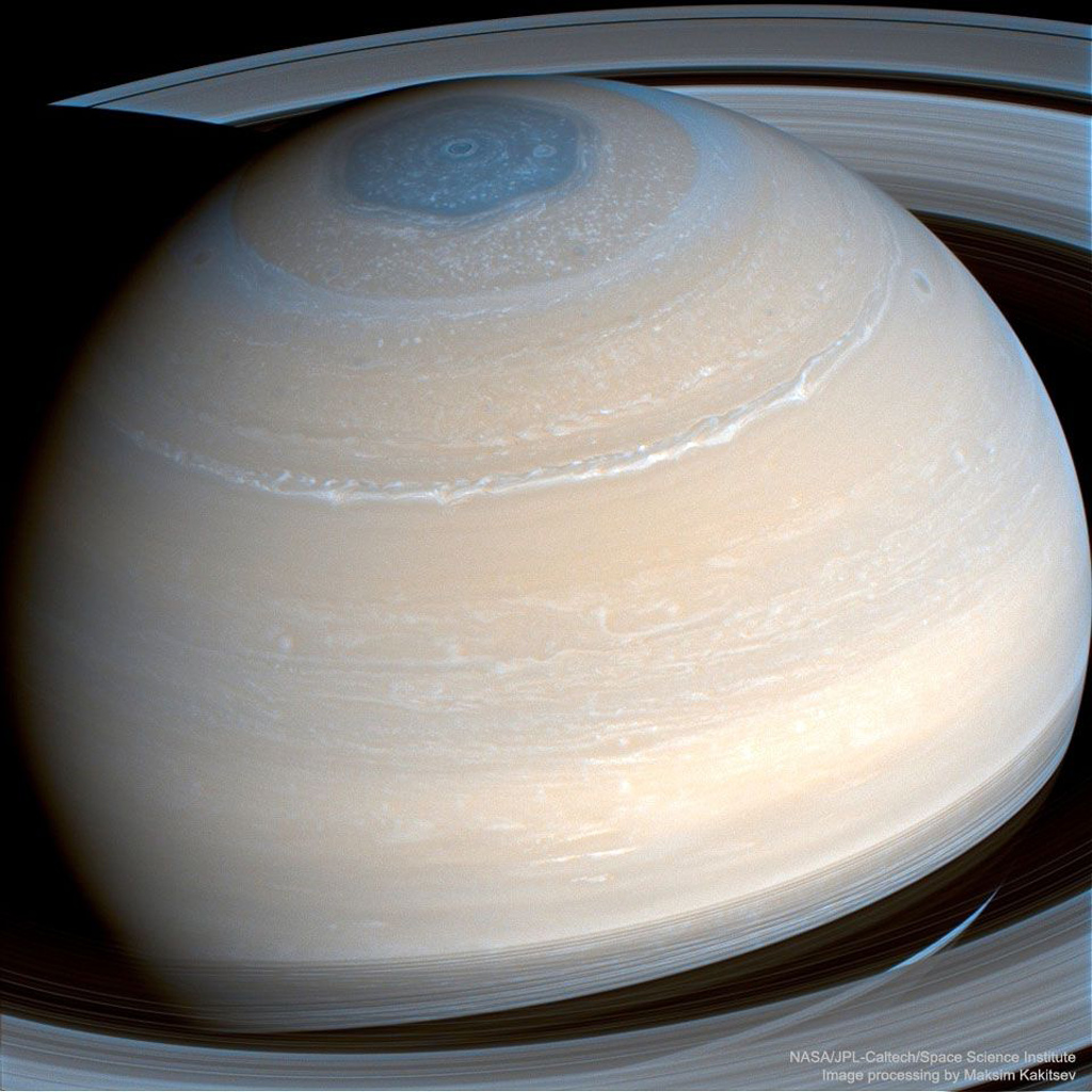 infrared view of Saturn from Cassini - Beige planet with white and blue rings around it.