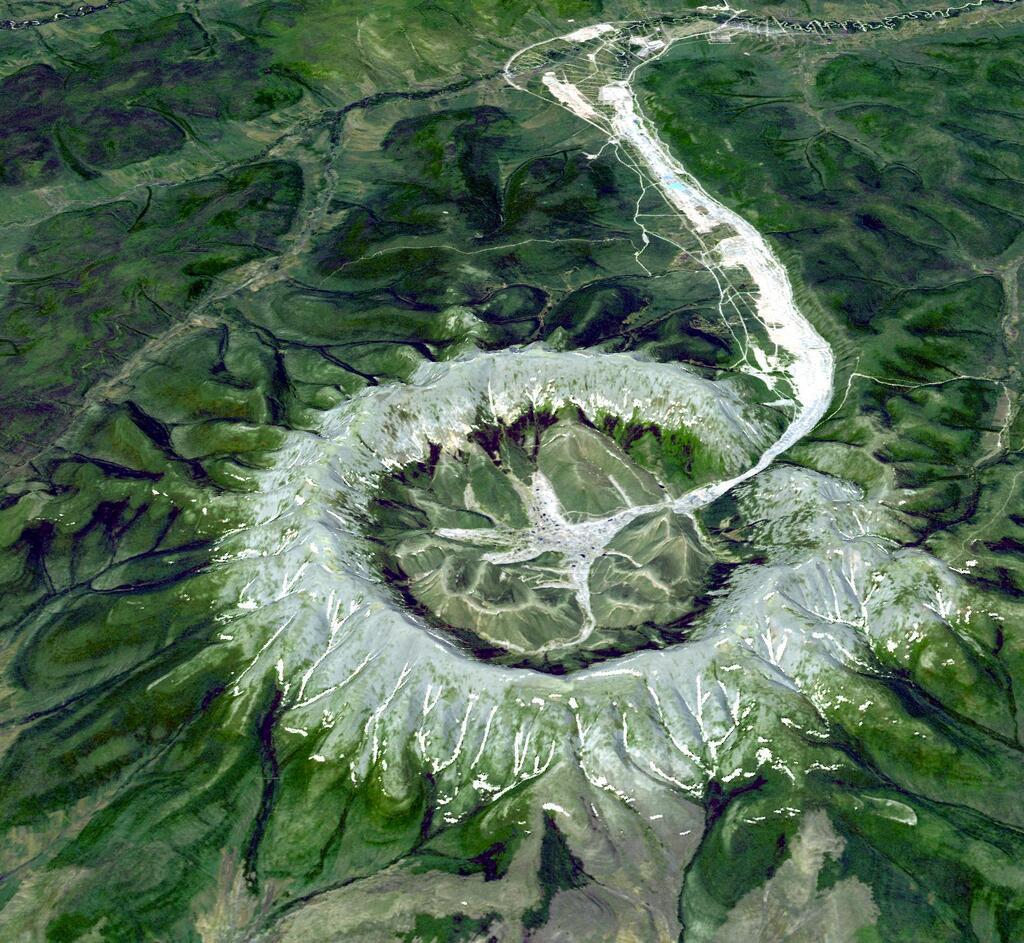 Aerial view of a crater-like phenomena on the green hills