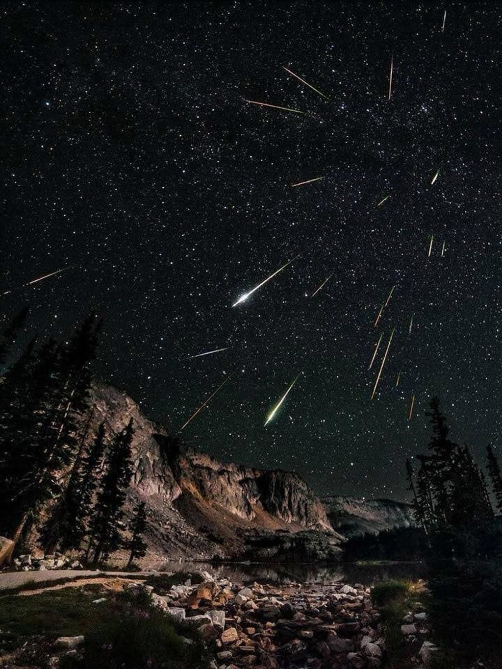 meteor showers in the night sky above mountains