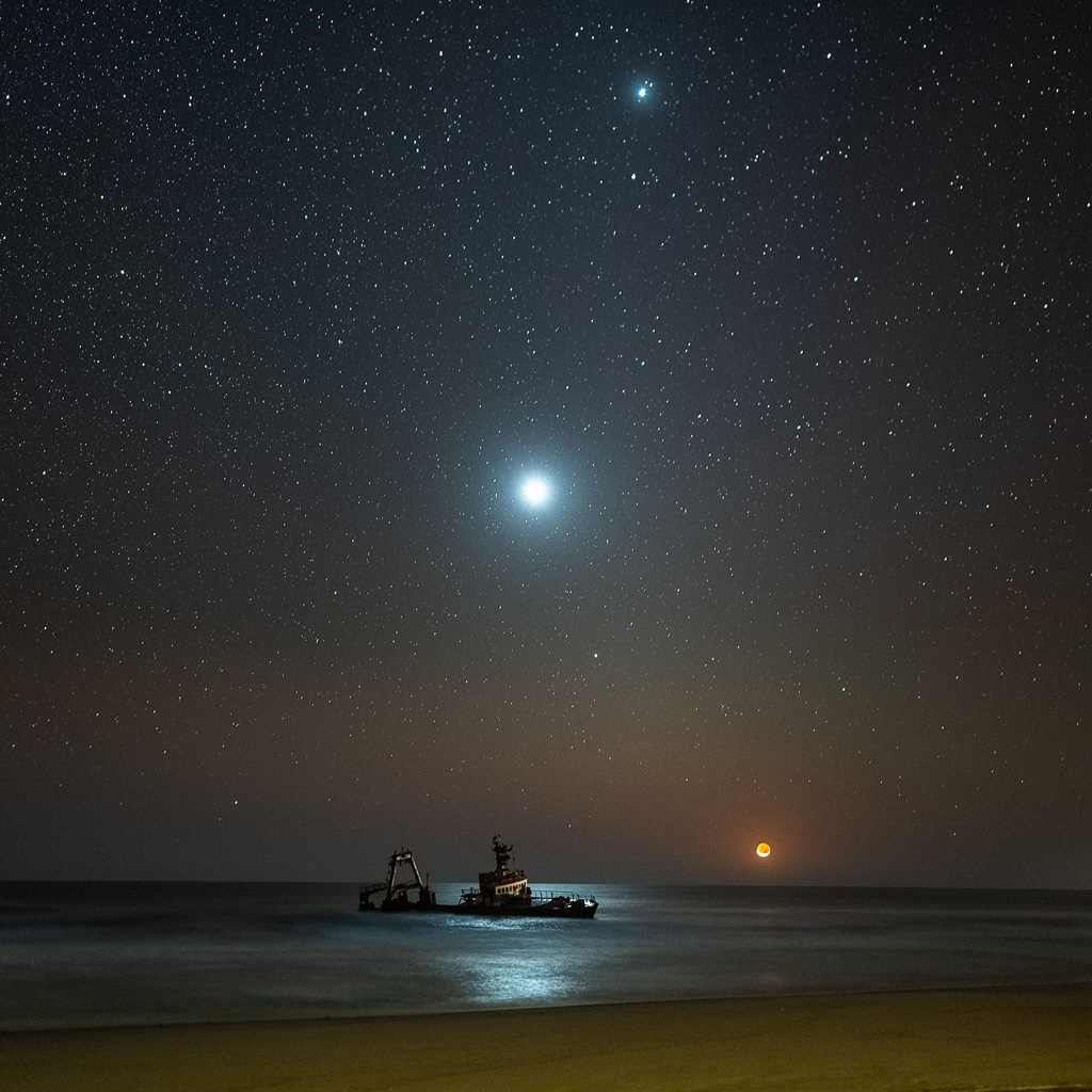 night image of a shipwreck on the beach under the moonlight
