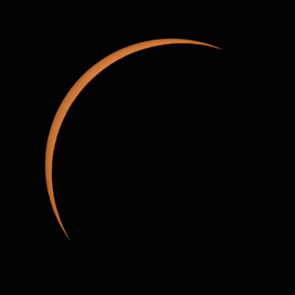 crescent view of the sun behind the black shadow of the moon.