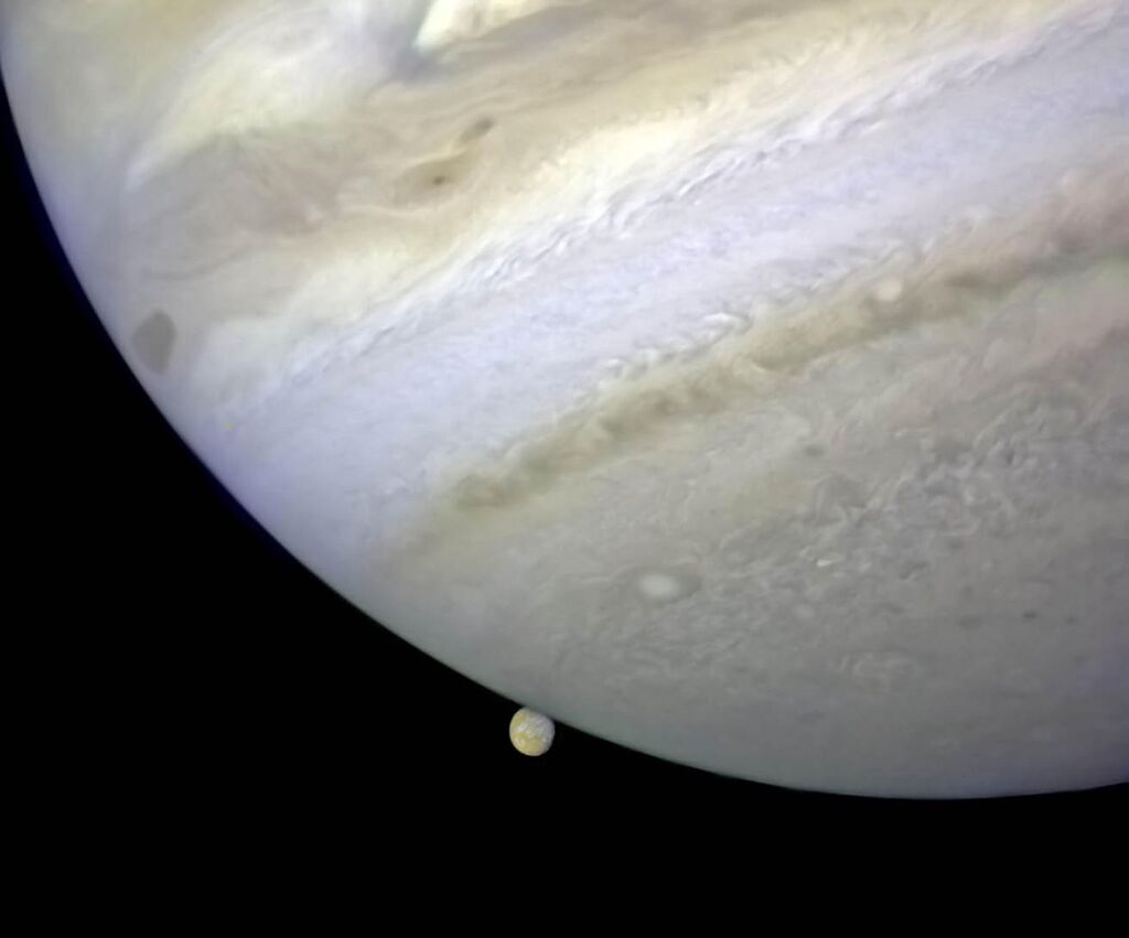 image of the surface of Jupiter with a small yellow moon 