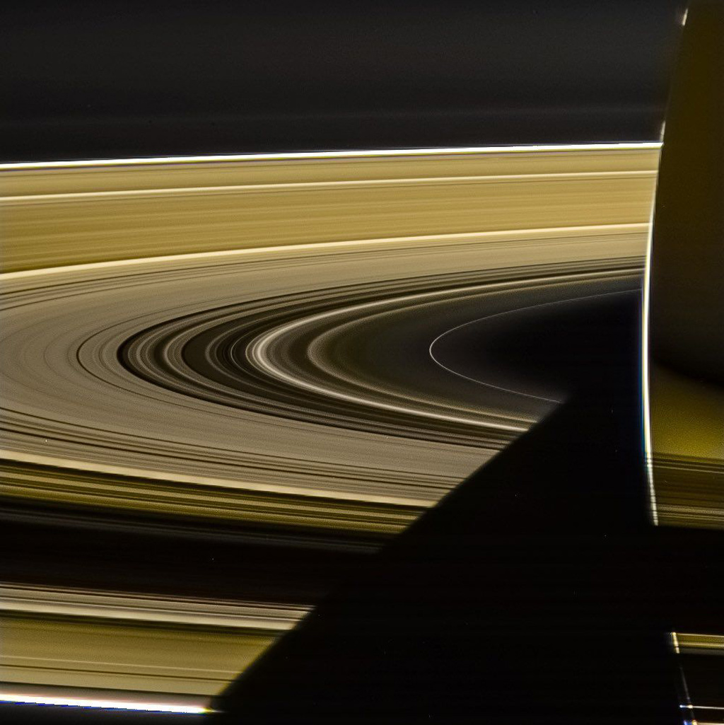 Close up image of Saturn and its yellow rings with the planet casting a shadow on them