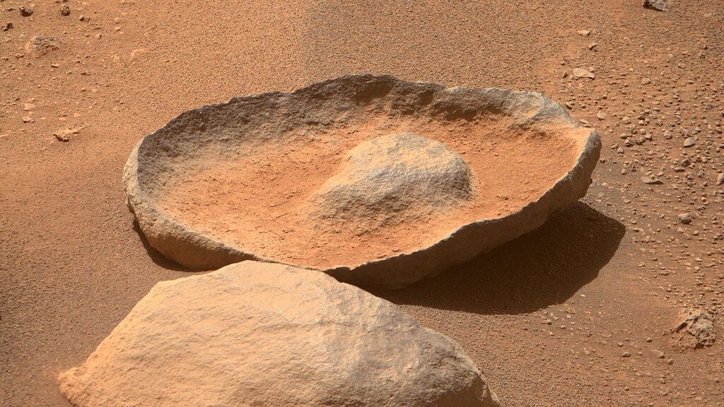 Image of a red rock on mars shaped like a plate with a hump in the middle