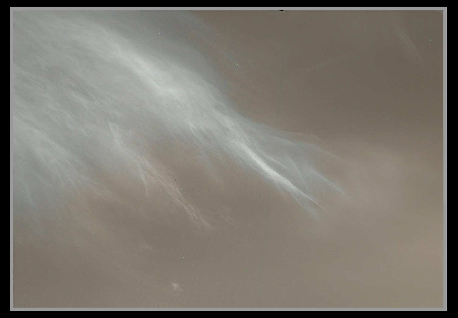 Thin wispy white clouds agains a dusty Martian sky.