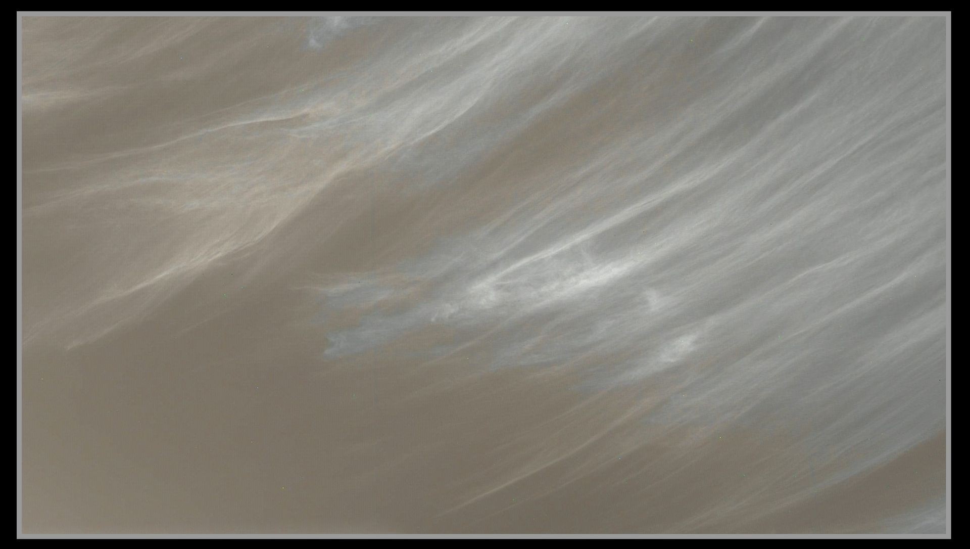 Thin wipsy white clouds agains a dusty Martian sky.