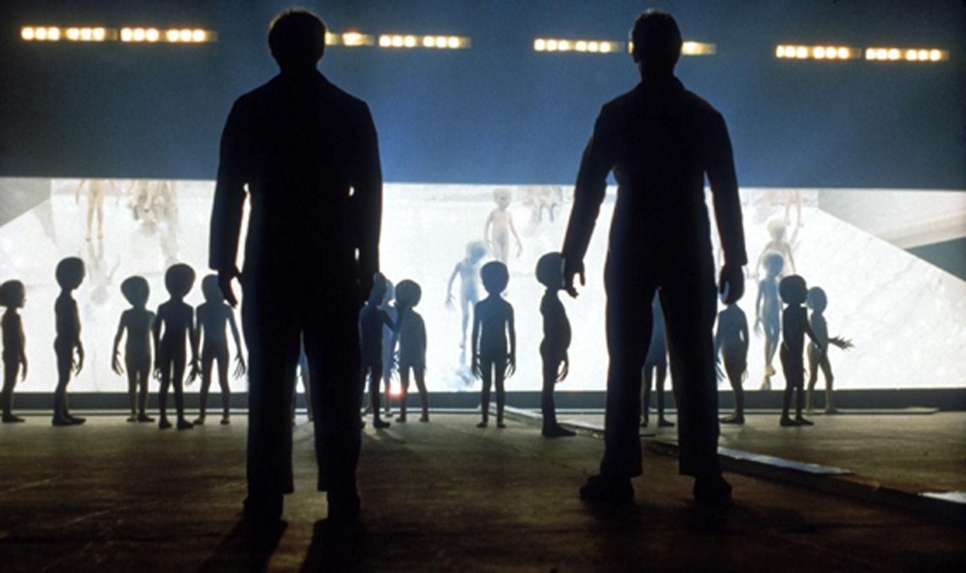 Image of two men looking at alien figures from the film Close Encounters of the Third Kind