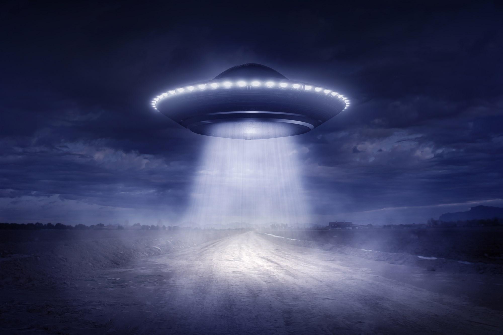 Image of a flyring saucer beaming down on a deserted road