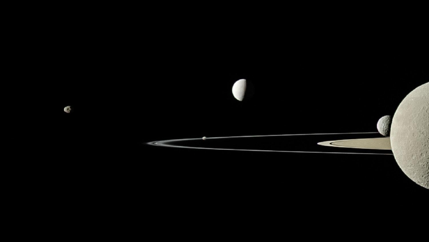 Side view image of Saturn, its rings, and its moons