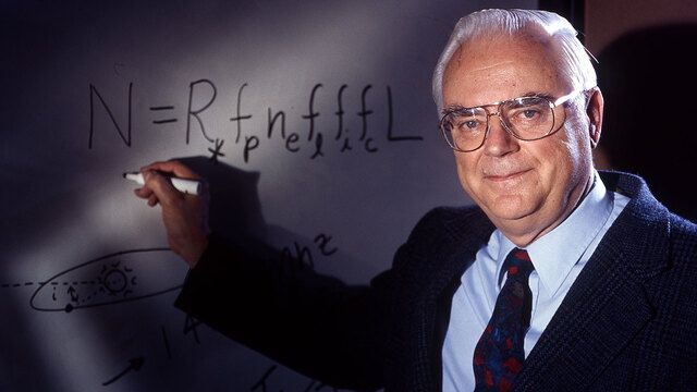 Frank Drake in front of a whiteboard with a pen pointing at his eponymous equation